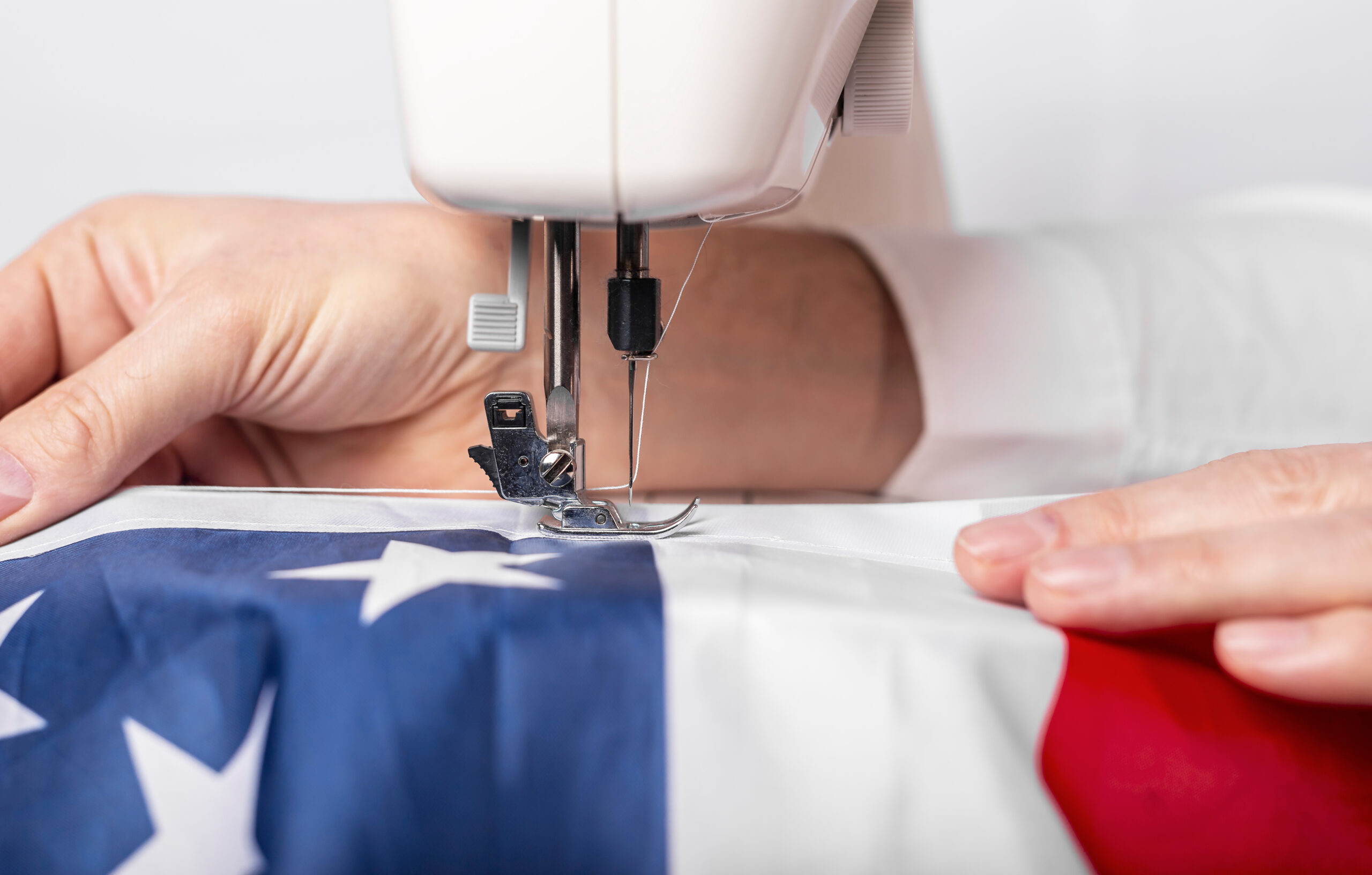 Male hands sewing american flag on sewing machine for us holiday.